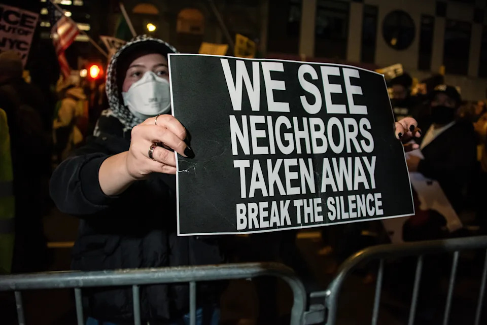 شخص يحمل لافتة احتجاجية مكتوب عليها: "نرى الجيران يؤخذون بعيدا. كسر الصمت،" في مظاهرة
