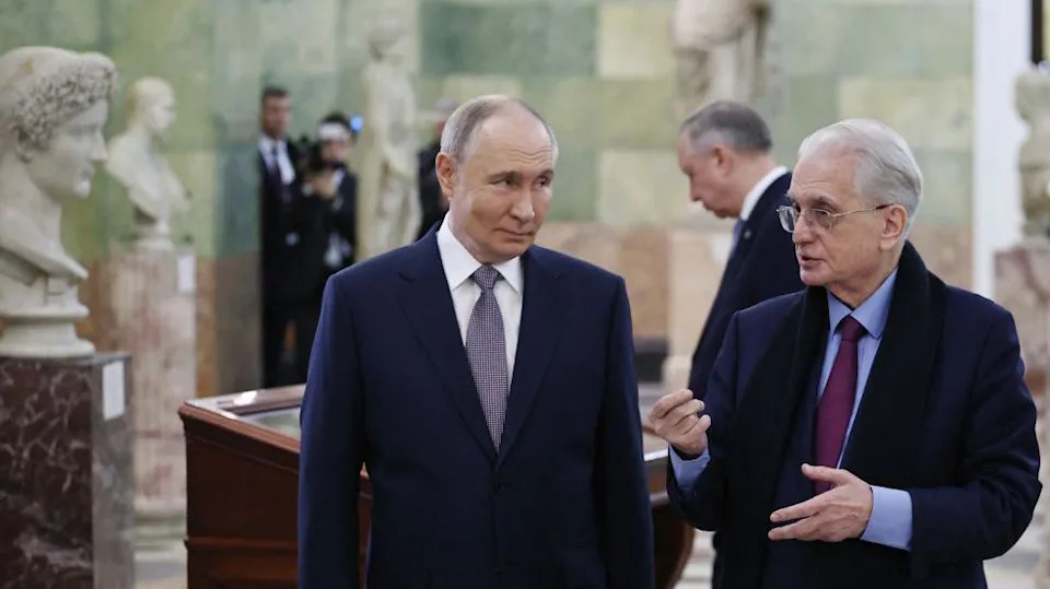 رجلان أبيضان في منتصف العمر في متحف فني محاطان بتماثيل نصفية قديمة