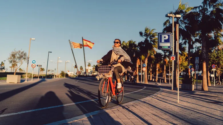 شخص يرتدي وشاحًا ويركب دراجة في شوارع فالنسيا غير المزدحمة