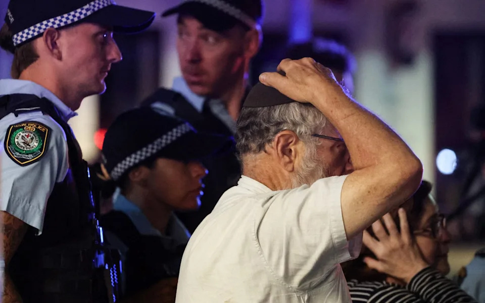 رد فعل أحد أفراد الجالية اليهودية بعدم التصديق والرعب أثناء سيره مع الشرطة نحو مكان إطلاق النار الجماعي يوم الأحد