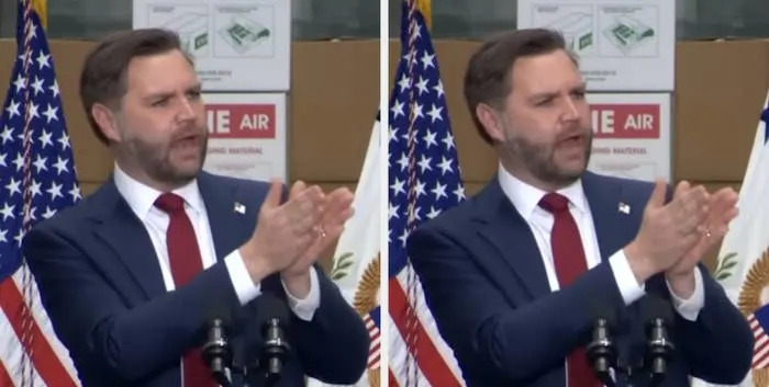 رجل يرتدي بدلة ويتحدث على منصة مع أعلام الولايات المتحدة في الخلفية