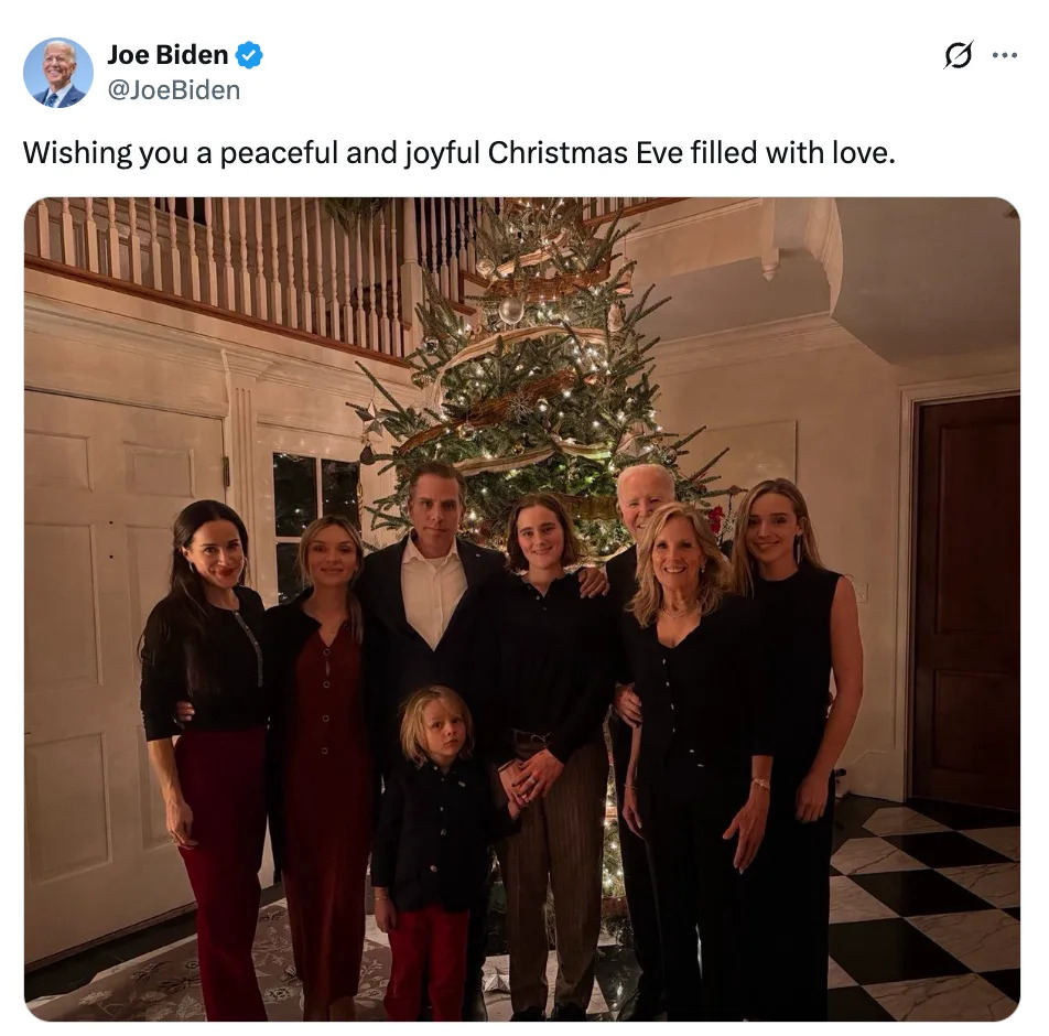 عائلة تقف أمام شجرة عيد الميلاد في غرفة مضاءة بشكل دافئ، مع رسالة تتمنى ليلة عيد ميلاد هادئة مليئة بالحب