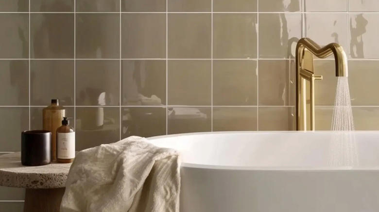 حمام بجدار من بلاط الزليج وحوض استحمام كبير بصنبور ذهبي.