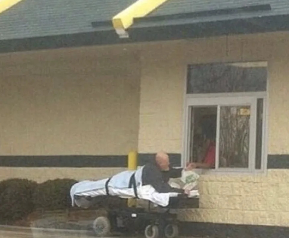 شخص على نقالة المستشفى يتلقى الطعام من نافذة السيارة