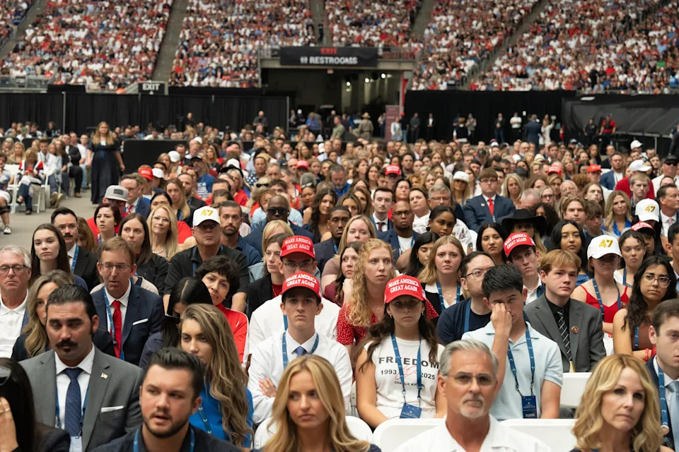 جمهور مكتظ في تجمع سياسي، حيث يرتدي العديد من الحاضرين قبعات حمراء