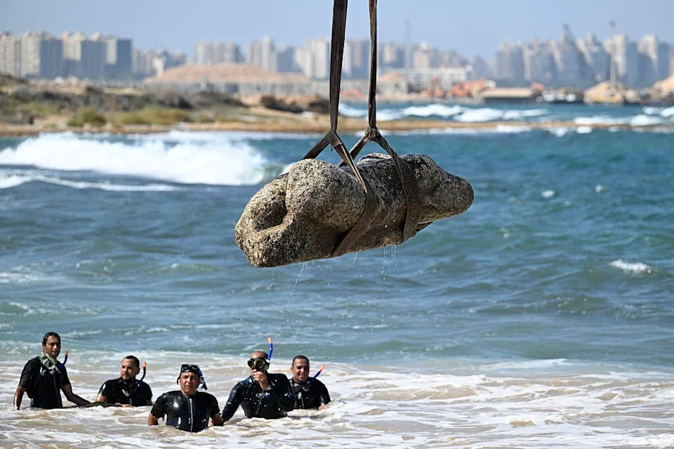 غواصون يشاهدون رافعة تسحب قطعة أثرية من المياه في خليج أبو قير بالإسكندرية في 21 أغسطس 2025، كجزء من الحدث الذي نظمته وزارة السياحة والآثار لاستعادة الآثار الغارقة. / تصوير: خالد دسوقي / وكالة الصحافة الفرنسية عبر Getty Images