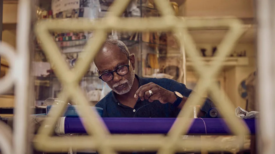 طه يخيط كيباه في متجره