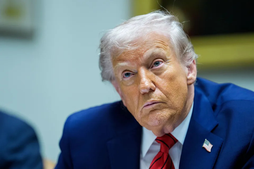 شخص يرتدي بدلة وعليها دبوس العلم الأمريكي يجلس في اجتماع وينظر إلى الاستبطان