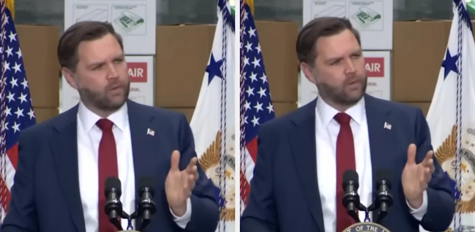 رجل يرتدي بدلة يتحدث على منصة مع أعلام في الخلفية