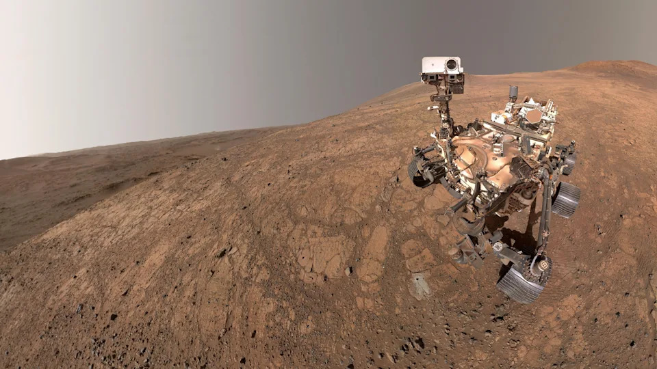 توجد مركبة جوالة على سطح المريخ ذو اللون البني المحمر