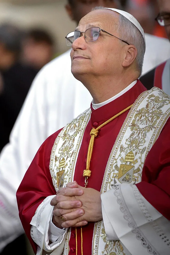 رجل يرتدي ملابس دينية مزخرفة، يشبك يديه معًا، وينظر إلى الأعلى متأملًا