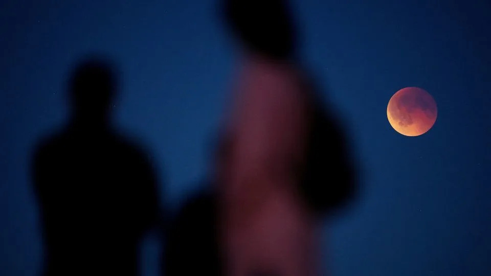 الناس يشاهدون القمر الدموي خلال خسوف القمر الكلي في كوغ، الدنمارك، في سبتمبر. - مادس كلوز راسموسن / ريتزاو سكانبيكس الدنمارك / رويترز