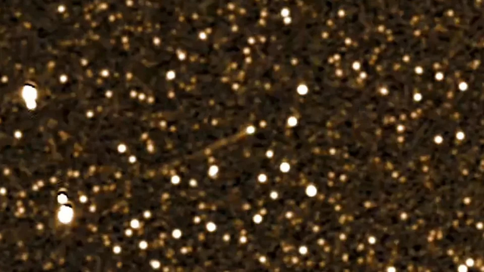 يظهر خط من الضوء الأبيض وسط صورة ذهبية مرصعة بالنجوم في الفضاء السحيق