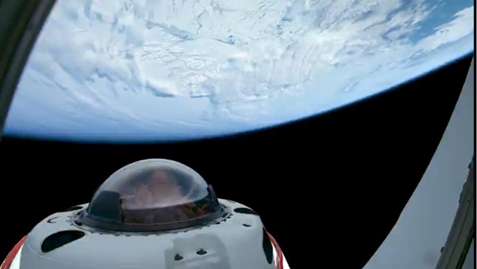 طرف مركبة فضائية ذات نافذة مقببة يطل على الأرض ذات الغطاء الأبيض.