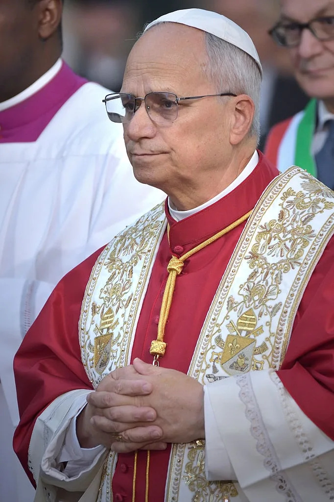 رجل يرتدي عباءة احتفالية مطرزة بالذهب ويقف متشابك اليدين، ويبدو وكأنه في حدث رسمي أو ديني