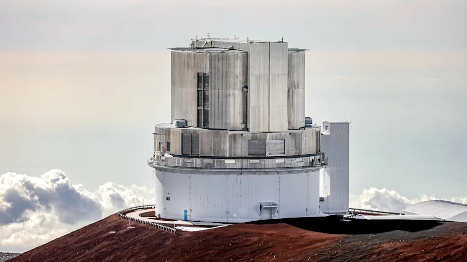 يقع مبنى معدني دائري كبير فوق منحدر صخري مع وجود غيوم في المسافة