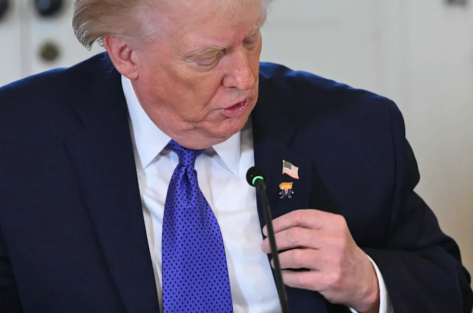 شخص يرتدي بدلة وربطة عنق يضبط دبوس العلم الأمريكي على طية صدر السترة، ويبدو مركزًا ومنتبهًا