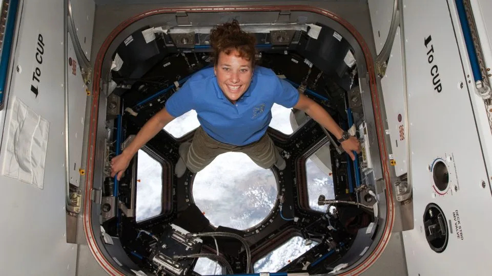 دوتي ميتكالف-ليندنبرجر تقف لالتقاط صورة لها في قبة محطة الفضاء الدولية في 17 أبريل 2010، بينما يظل مكوك الفضاء ديسكفري راسيًا بالمحطة. - ناسا