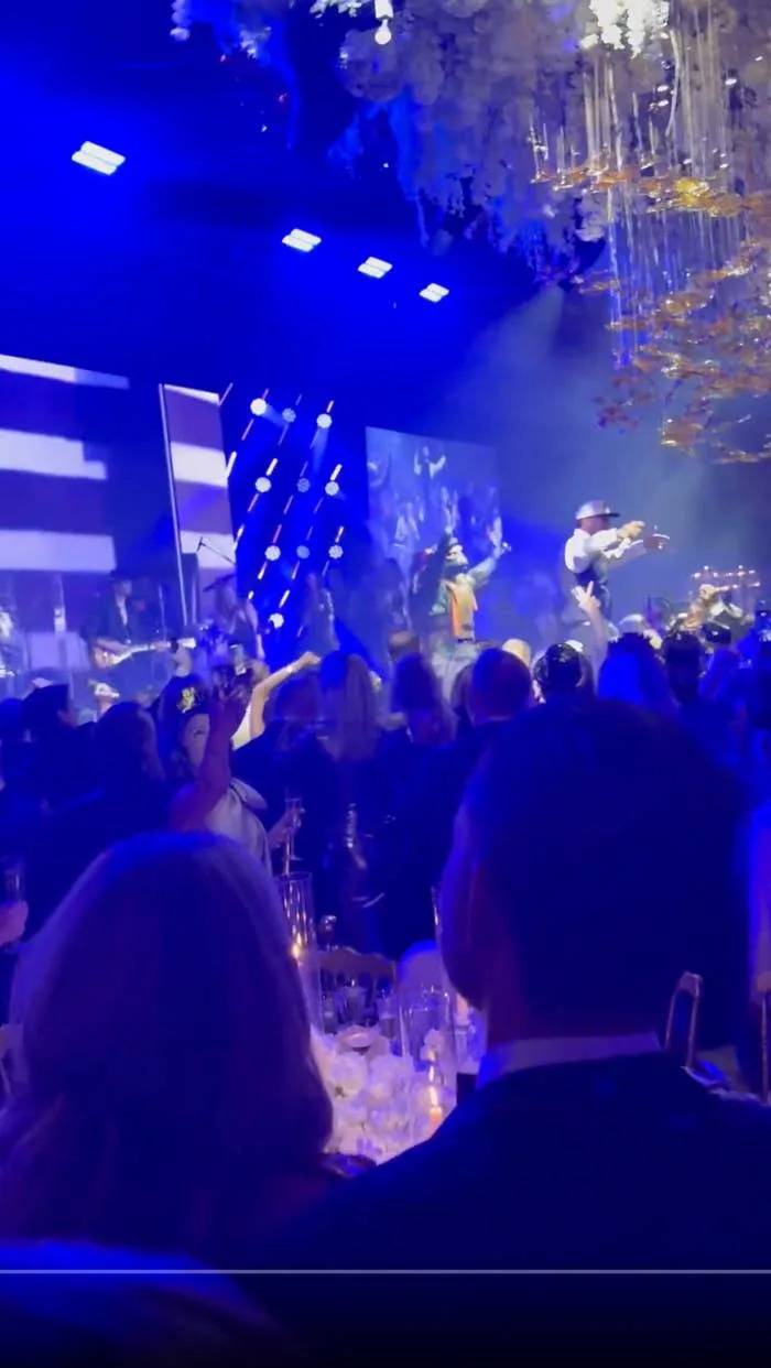 أشخاص يستمتعون بحفل موسيقي حي في مكان داخلي نابض بالحياة مزود بأضواء وديكورات على المسرح