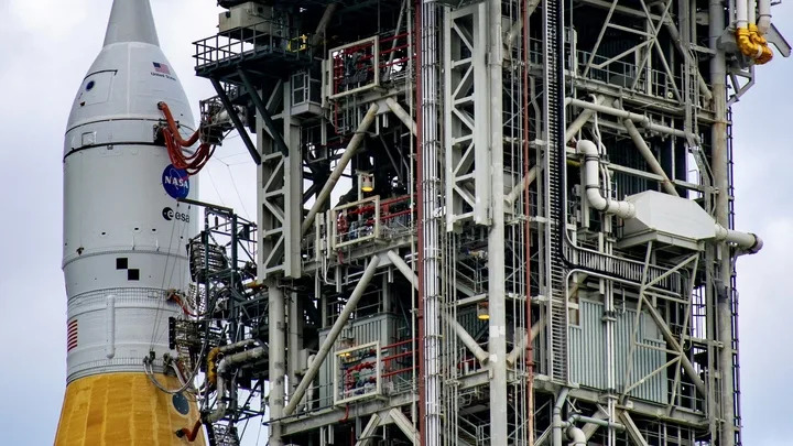 صاروخ برتقالي ذو قمة بيضاء بجوار برج الإطلاق.