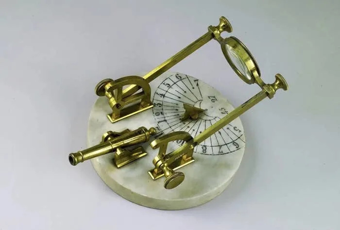 مزولة شمسية من النحاس العتيق مع بوصلة ومستوى على قاعدة رخامية مستديرة، تظهر عليها أرقام رومانية