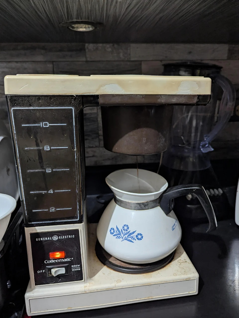 ماكينة تحضير القهوة في إبريق مزخرف بالزهور على طاولة المطبخ