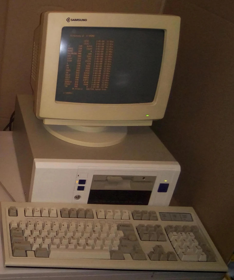 جهازان للكمبيوتر: أحدهما حديث بشاشة مسطحة يعرض الطريق ونظام التشغيل، والآخر عبارة عن جهاز قديم مزود بشاشة كبيرة الحجم تعرض نصًا برتقاليًا