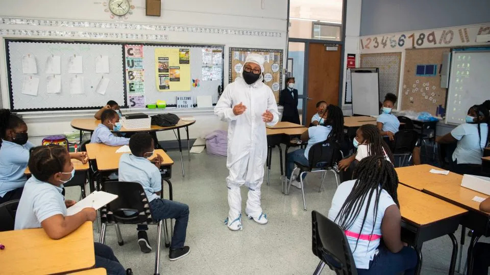 شوهد كينيث هاريس الثاني يرتدي بدلة أرنب، تم ارتداؤها أثناء تجميع المركبة الفضائية لمنع التلوث، بينما كان يتحدث مع الطلاب في 18 نوفمبر 2021، في مدرسة غارفيلد الابتدائية في واشنطن العاصمة. - جويل كوسكي/ناسا