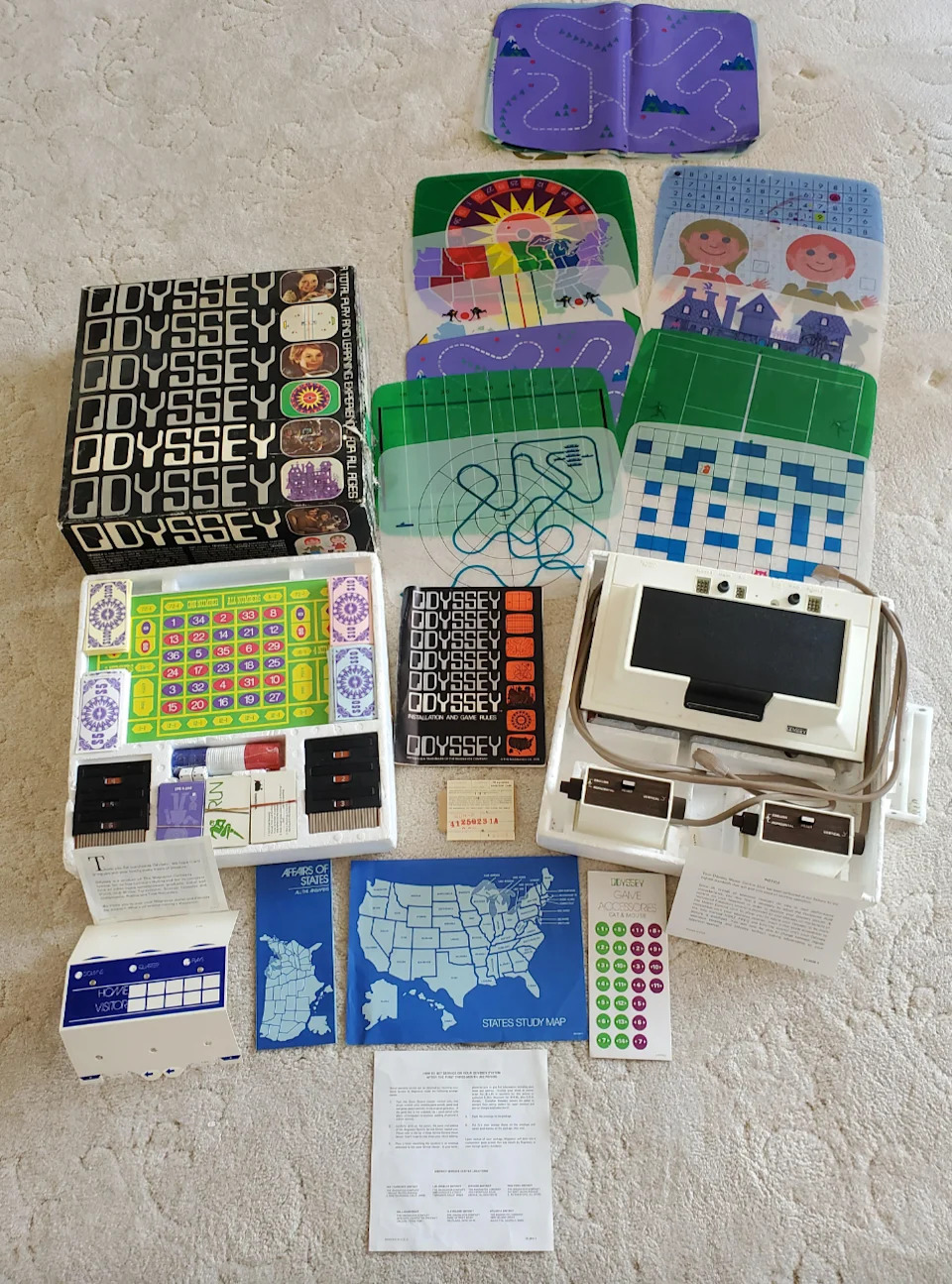 مجموعة وحدة التحكم Magnavox Odyssey مع لوحات ألعاب وبطاقات وكتيبات معروضة على السجادة