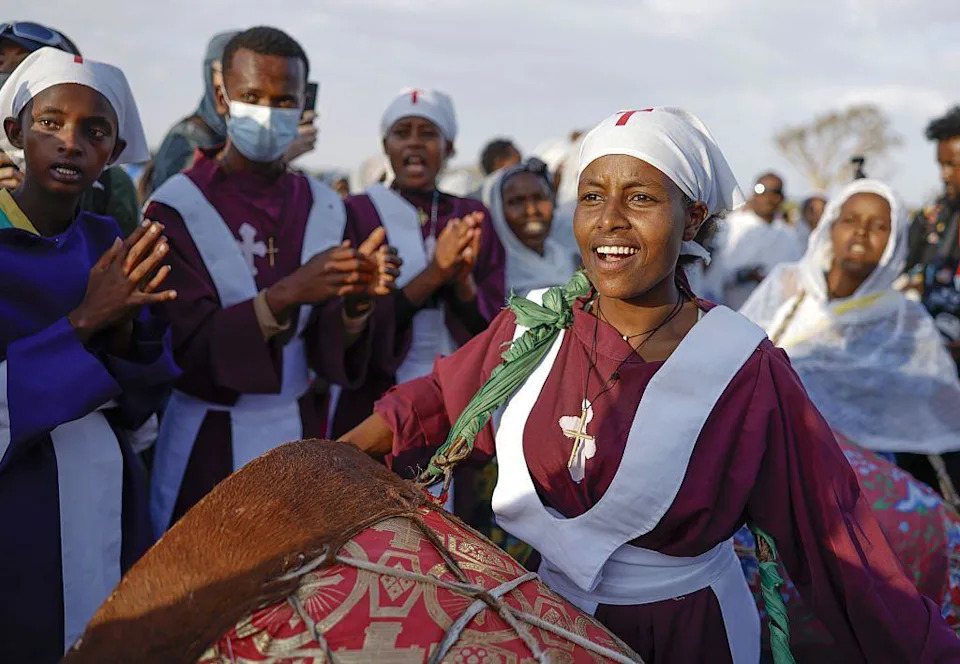 امرأة ترتدي قميصًا أرجوانيًا تهتف بصوت عالٍ على الطبل.