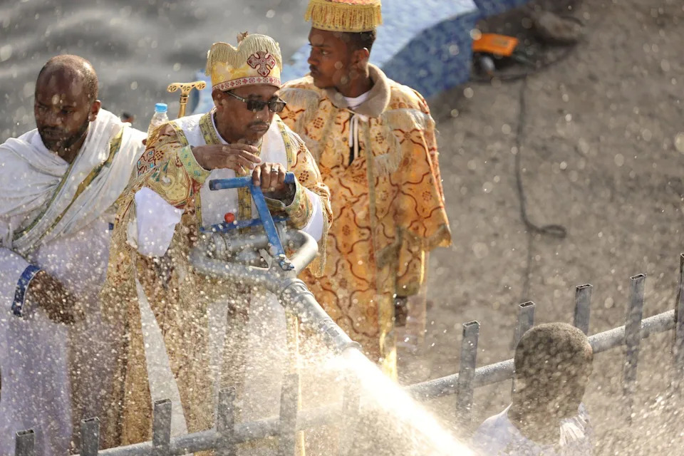 يستخدم الكاهن خرطومًا كبيرًا لتعميد الأشخاص الذين يشاهدونه.