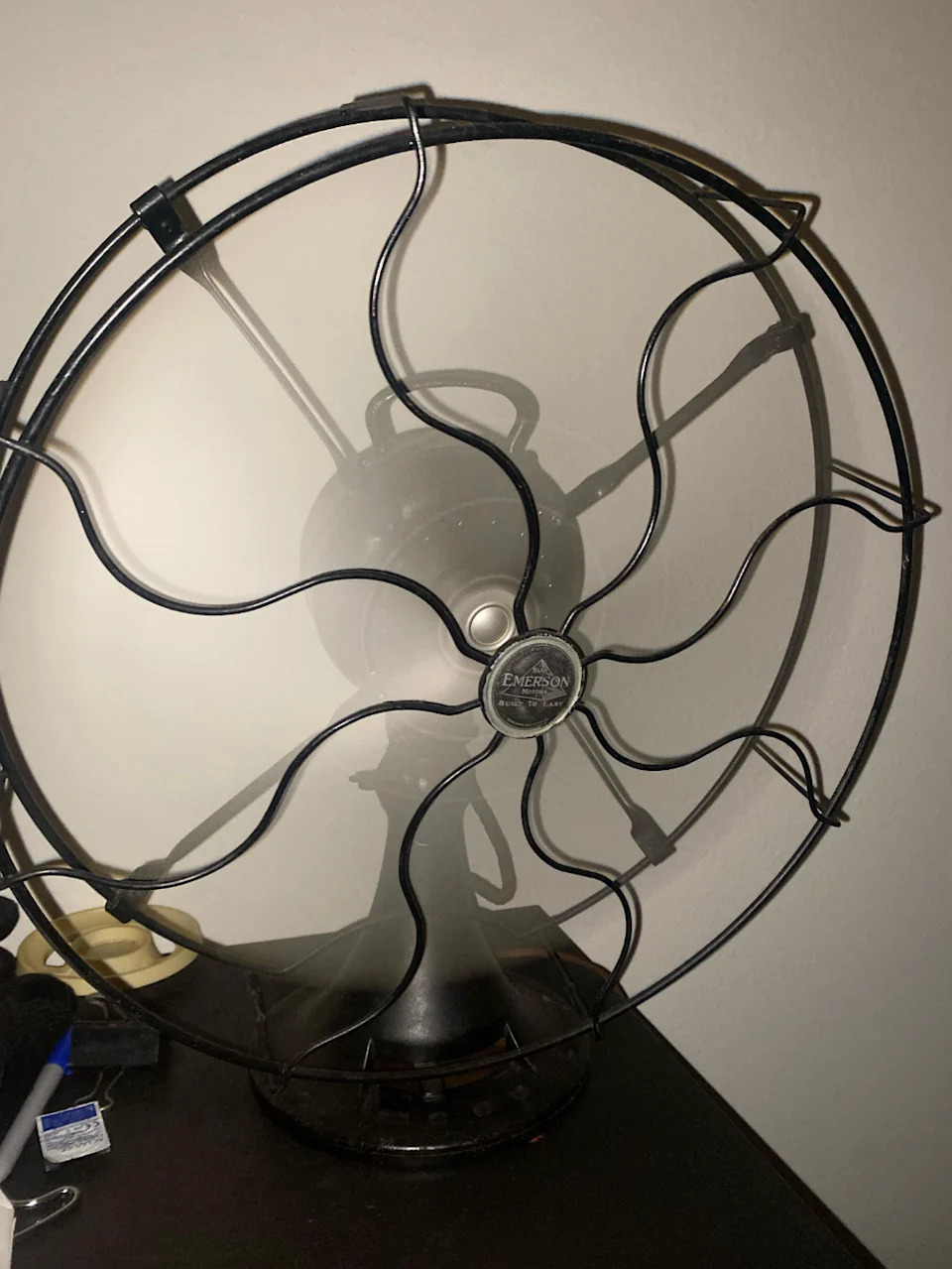 توجد مروحة كهربائية عتيقة من Emerson ذات أنماط شواية معدنية معقدة على طاولة