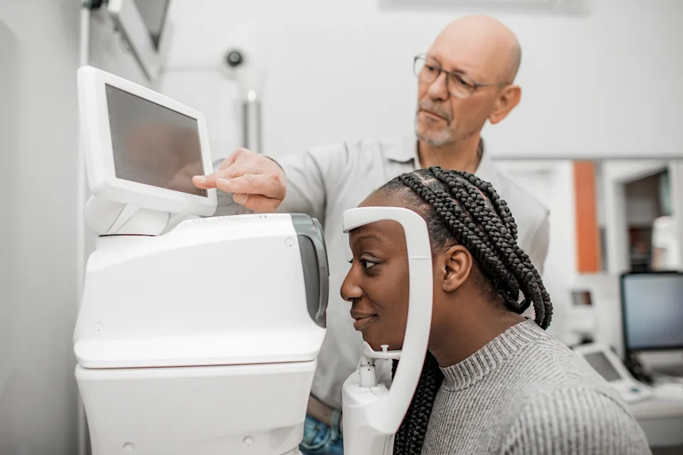 شخص يخضع لفحص العين في عيادة طبيب العيون، باستخدام جهاز رقمي، بمساعدة متخصص